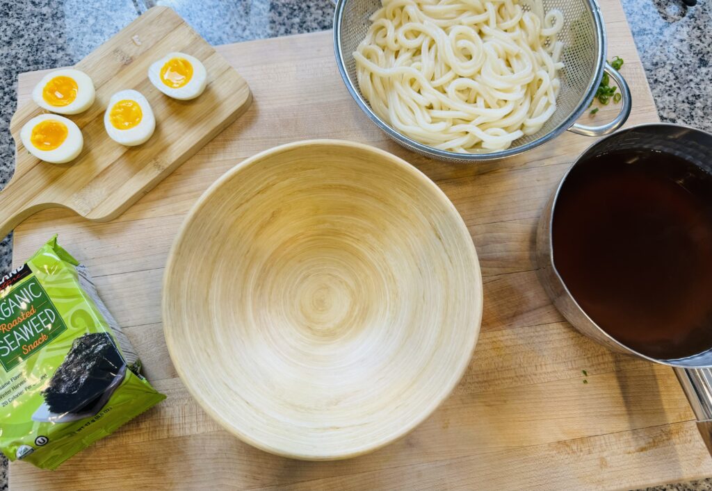 The ingredients ready to be assembled: soft boiled eggs, udon noodles, broth, seaweed