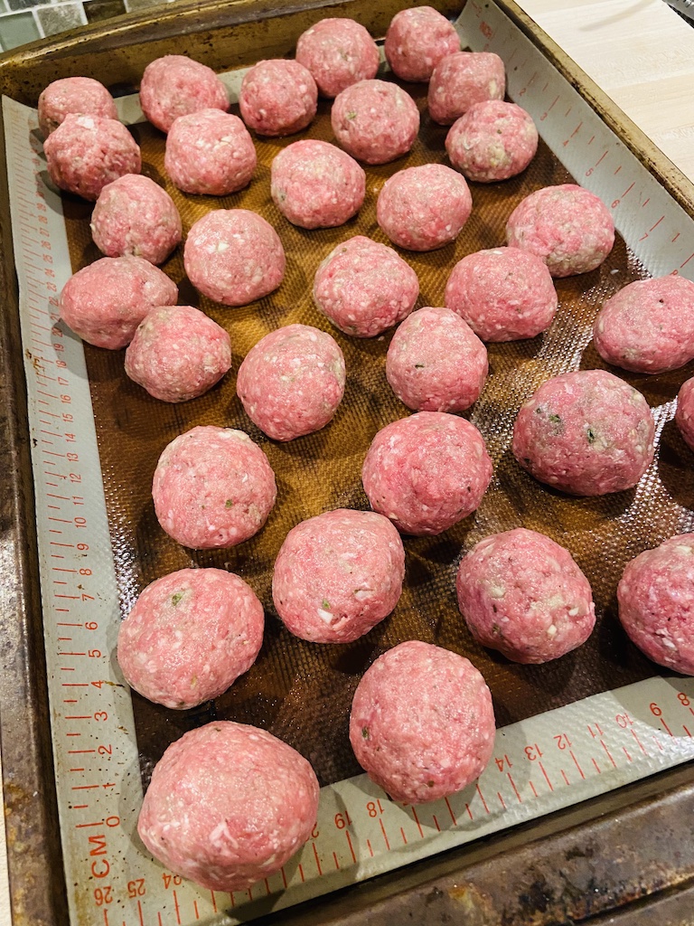 Rolled raw meatballs on baking pan