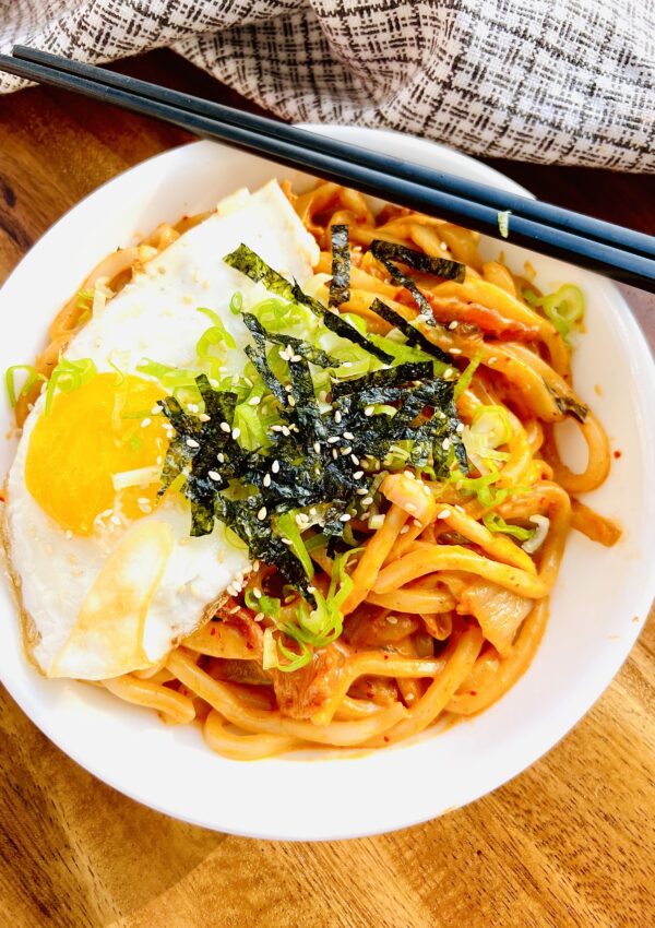 bowl of kimchi udon noodles with egg and seaweed