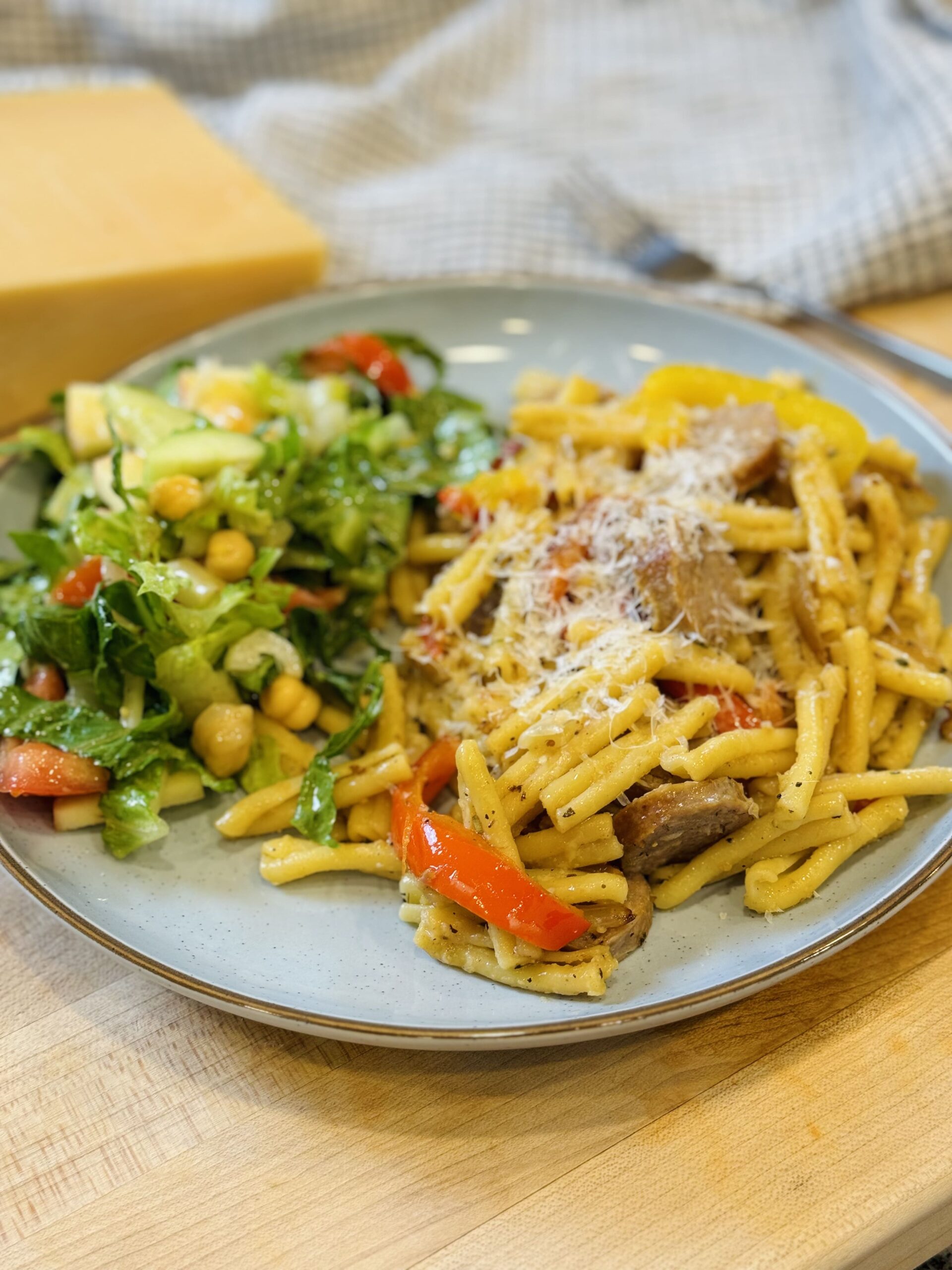 final dish of sausage and pepper pasta on a plate with salad pairing
