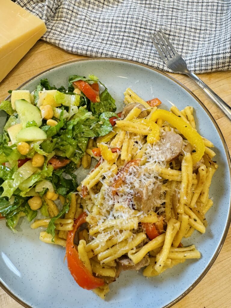 finished sausage and pepper pasta on a plate with salad pairing