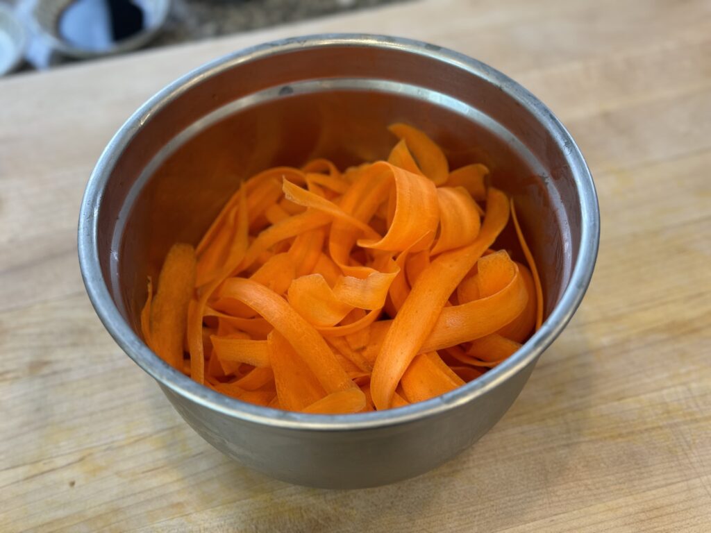 carrots sliced into thin ribbons in a cooking bowl