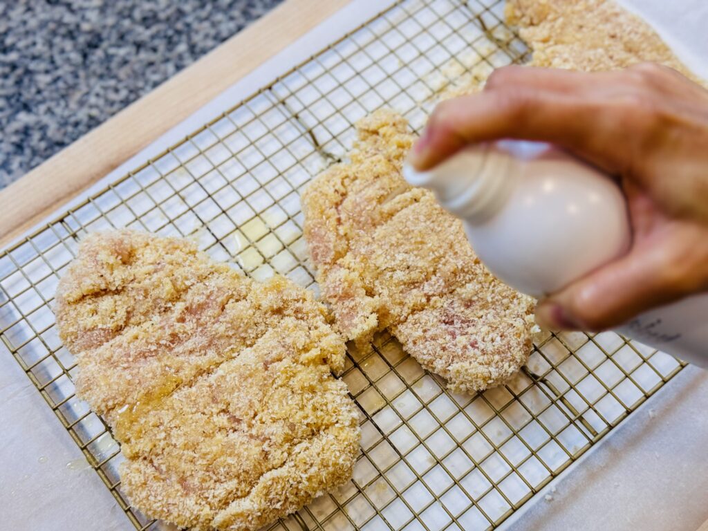 spraying breaded chicken with avocado oil