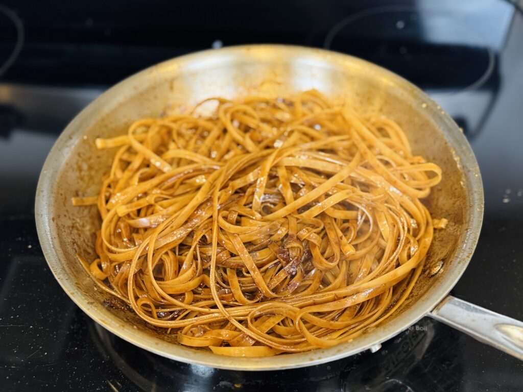 Cooked rice noodles and sauce to the pan