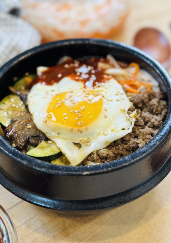 One Pan Bibimbap – Korean Rice Bowl and pickled carrots and Korean Gochujang Sauce on the background