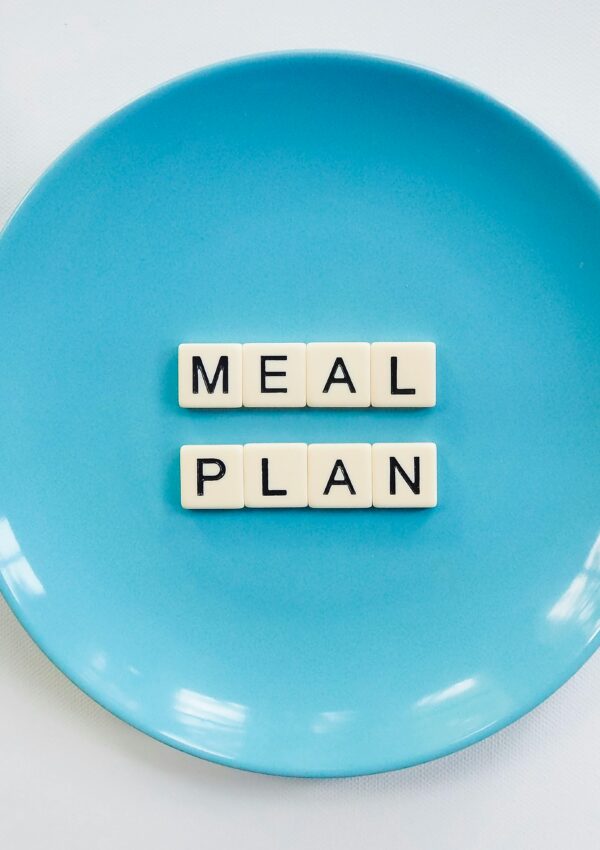 Innovative meal planning concept using alphabet tiles on a blue plate with green leaves.