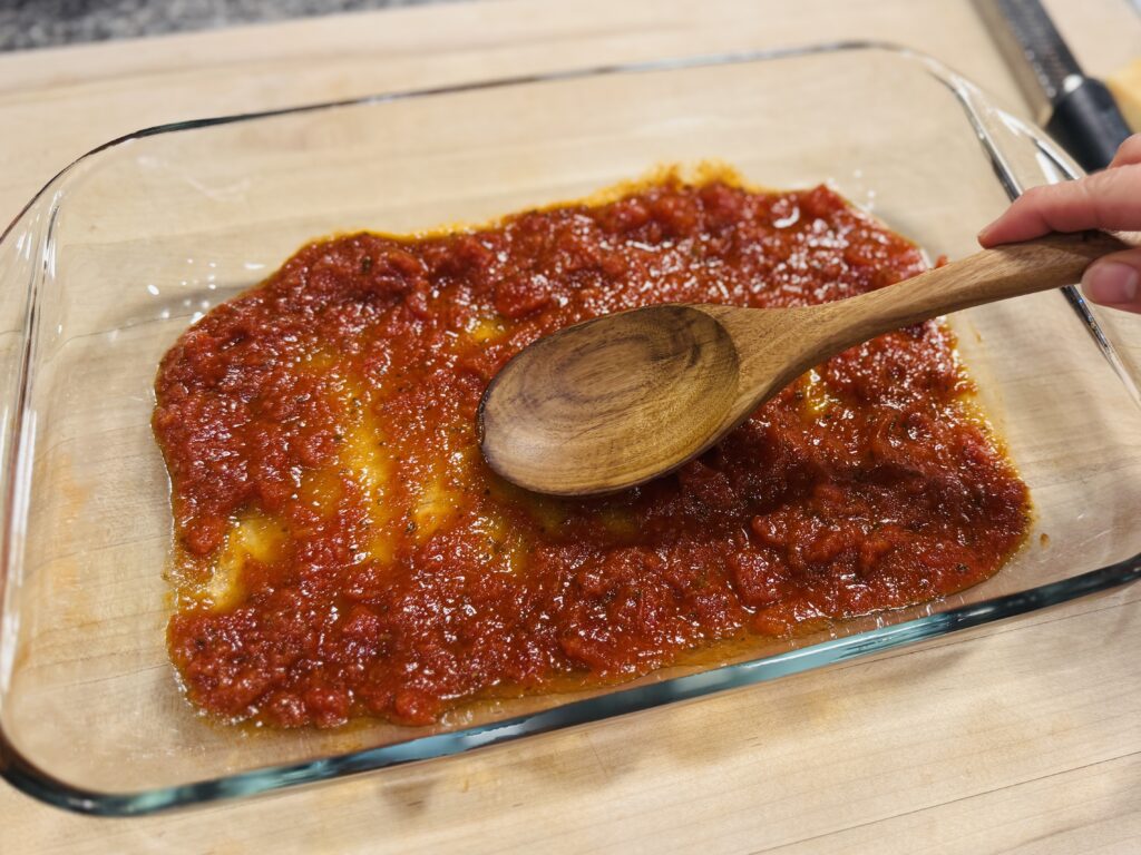 Spread a cup of marinara sauce on the baking dish.