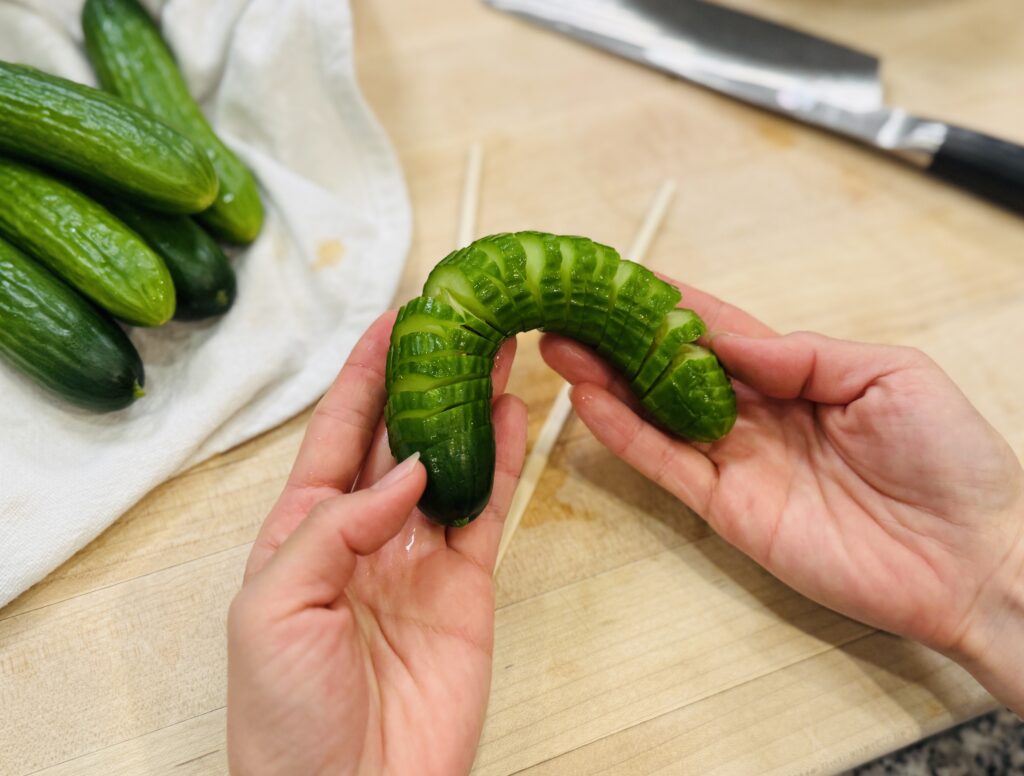 Spiralized baby cucumber being fanned out to show spiralized shape after slicing