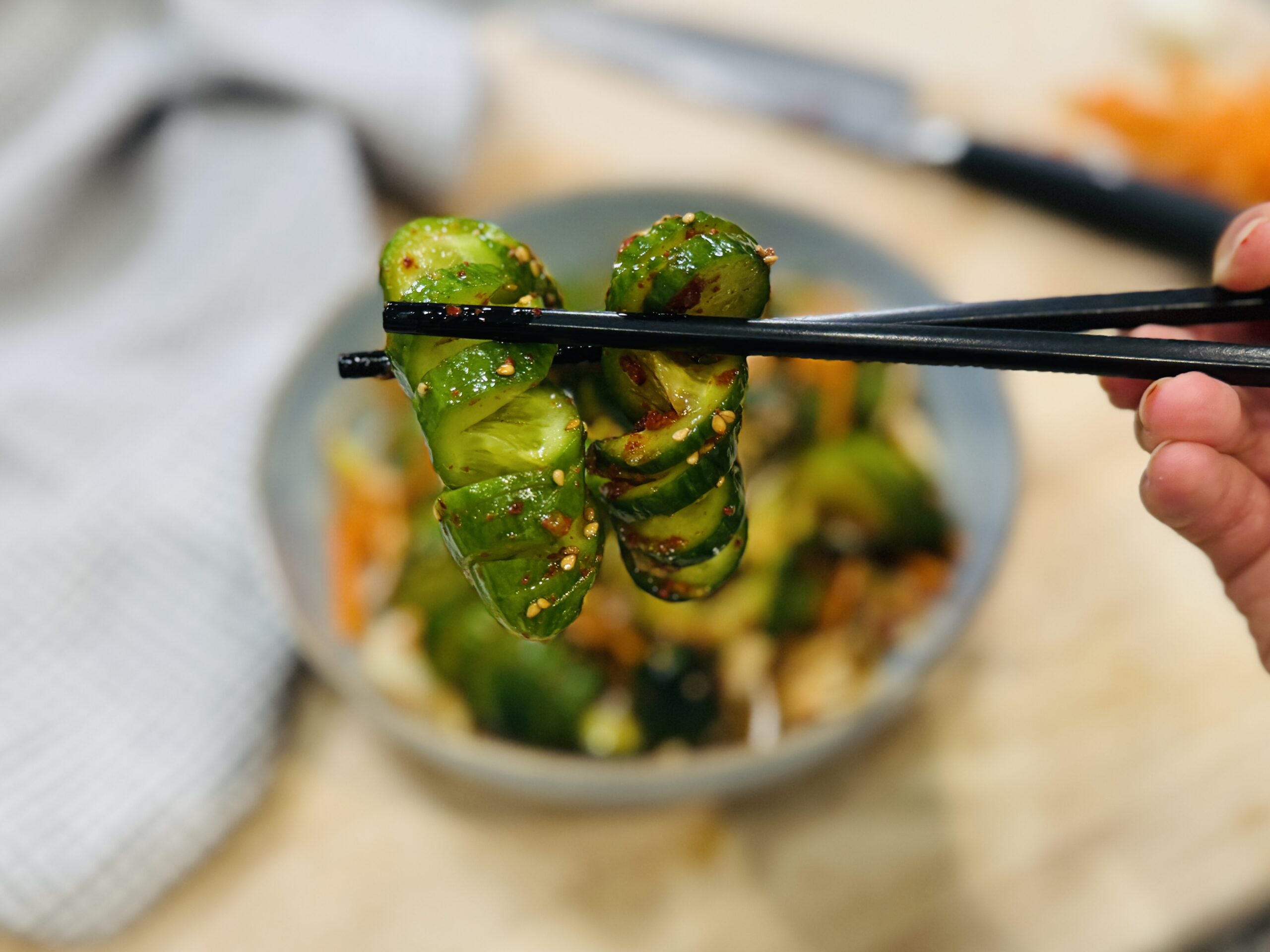 Close up of spiral cucumber salad held by chopsticks