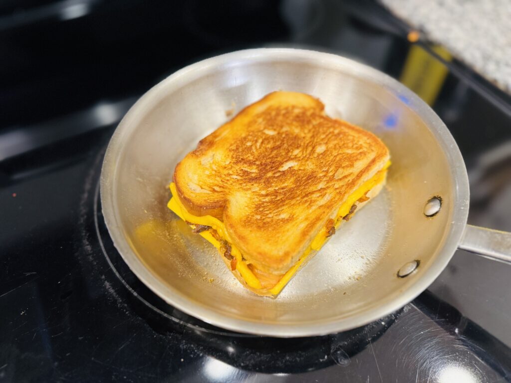 Kimchi grilled cheese being assembled in a skillet — sourdough bread with American cheese, kimchi, and bulgogi filling layered inside