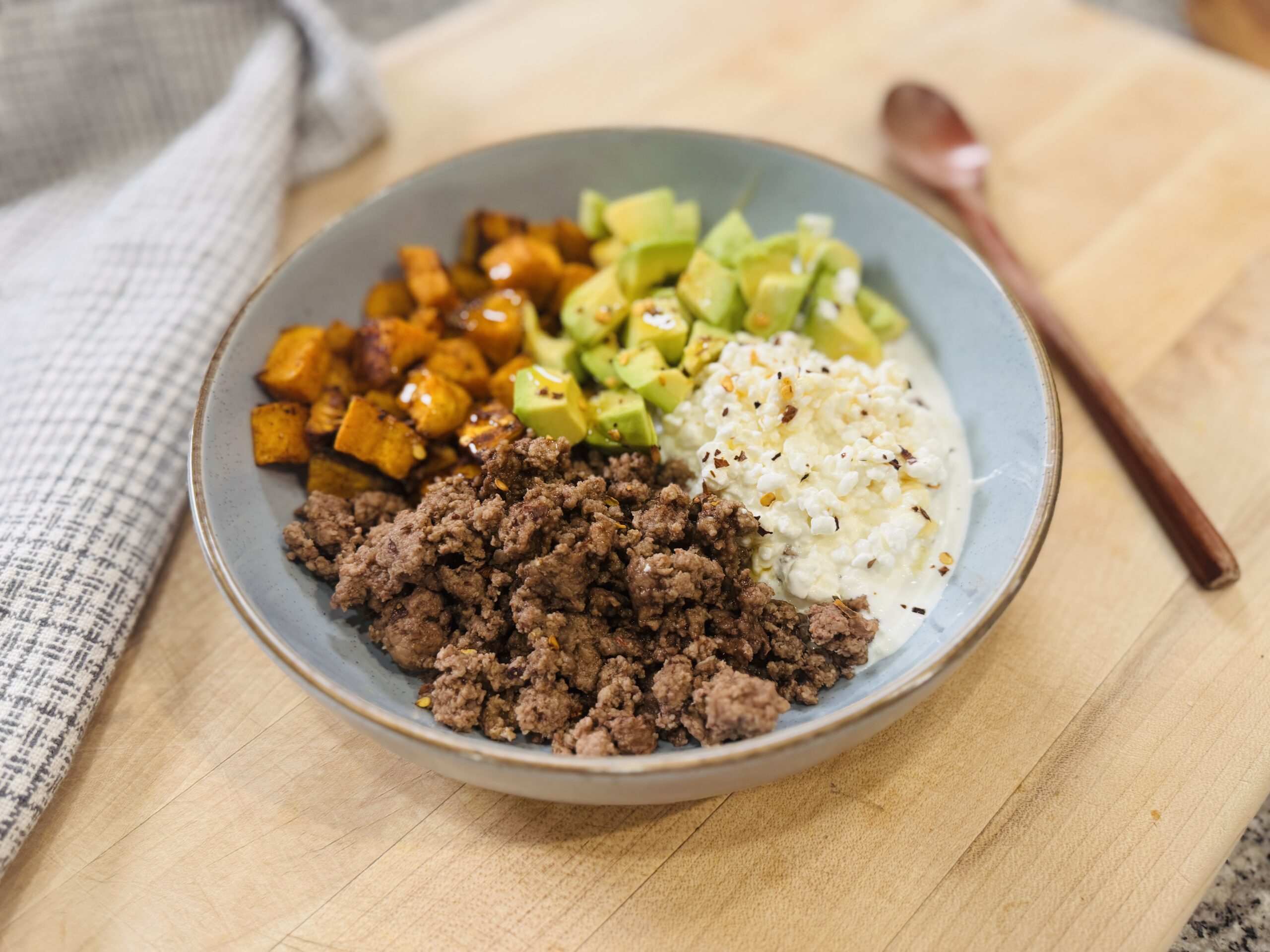 Ground beef sweet potato cottage cheese bowl with roasted sweet potatoes, seasoned ground beef, creamy cottage cheese, cubed avocado, and a drizzle of hot honey