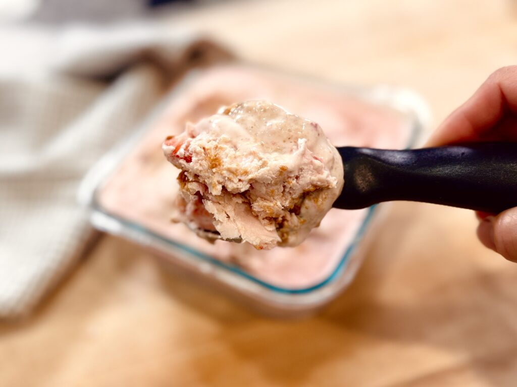Close-up of a scoop of strawberry Biscoff cottage cheese ice cream after freezing, showing the texture once softened and ready to serve