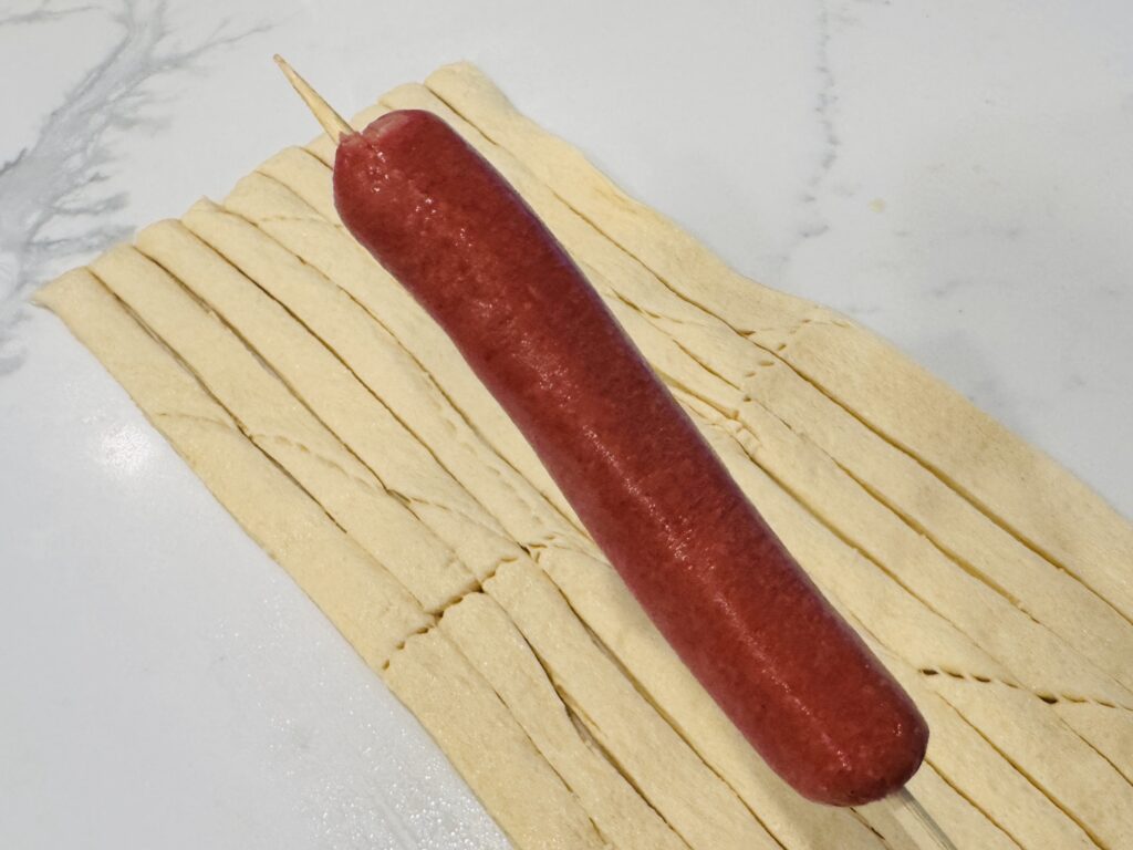 Close-up of a hot dog on a wooden skewer with approximately 2 inches of skewer exposed at the top, leaving room for the cheddar cheese star.