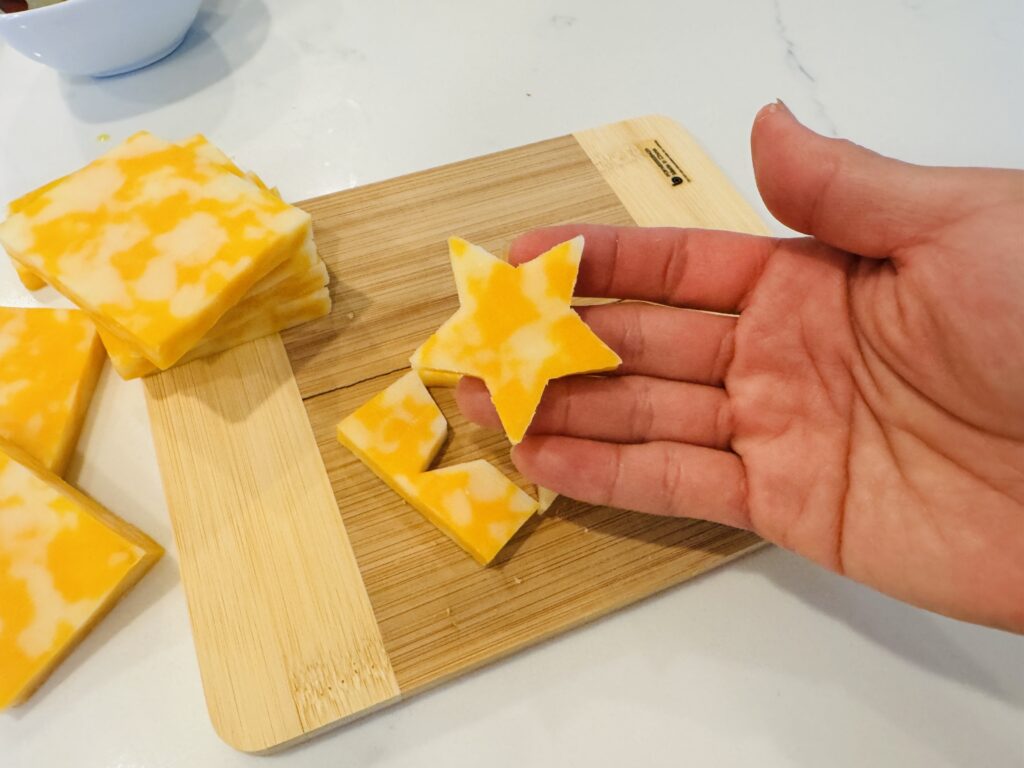 Close-up of star-shaped cheddar cheese pieces cut with a small cookie cutter for topping firecracker hot dogs