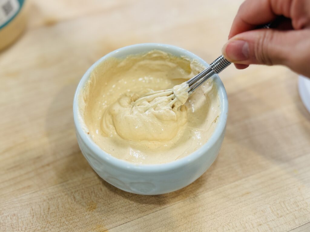 Whisking peanut butter into Greek yogurt for magic shell yogurt
