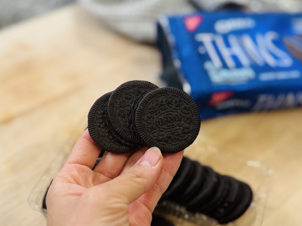 Three Oreo cookies with a bag of Oreo Thins in the background