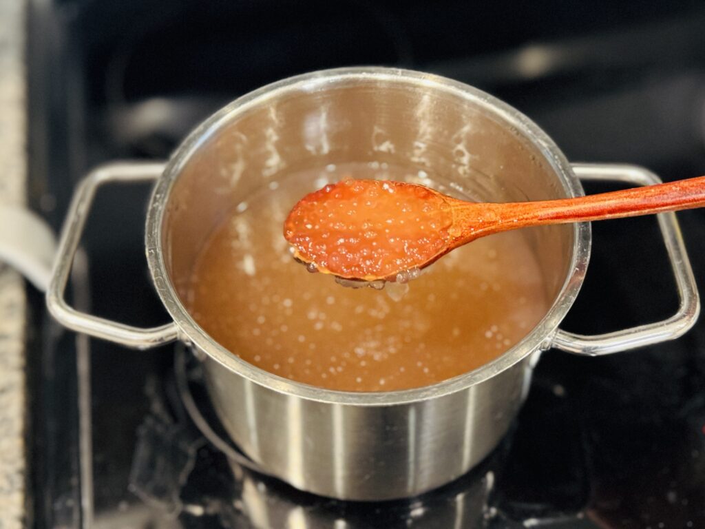 Spoonful of cooked, translucent mini tapioca pearls held over the pot