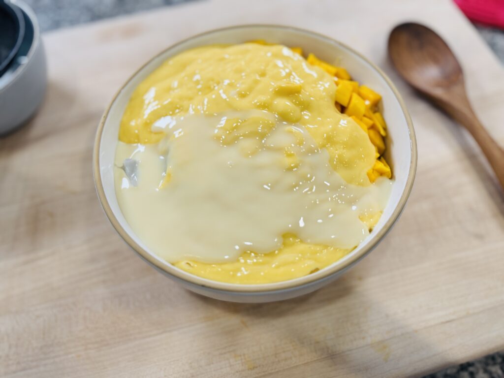 Large bowl with cooked sago, chopped mango, coconut jelly, and mango coconut blend before mixing