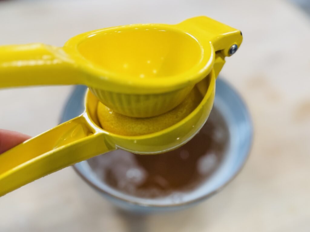 Fresh lemon juice being squeezed by hand into the warm apple juice and gelatin mixture