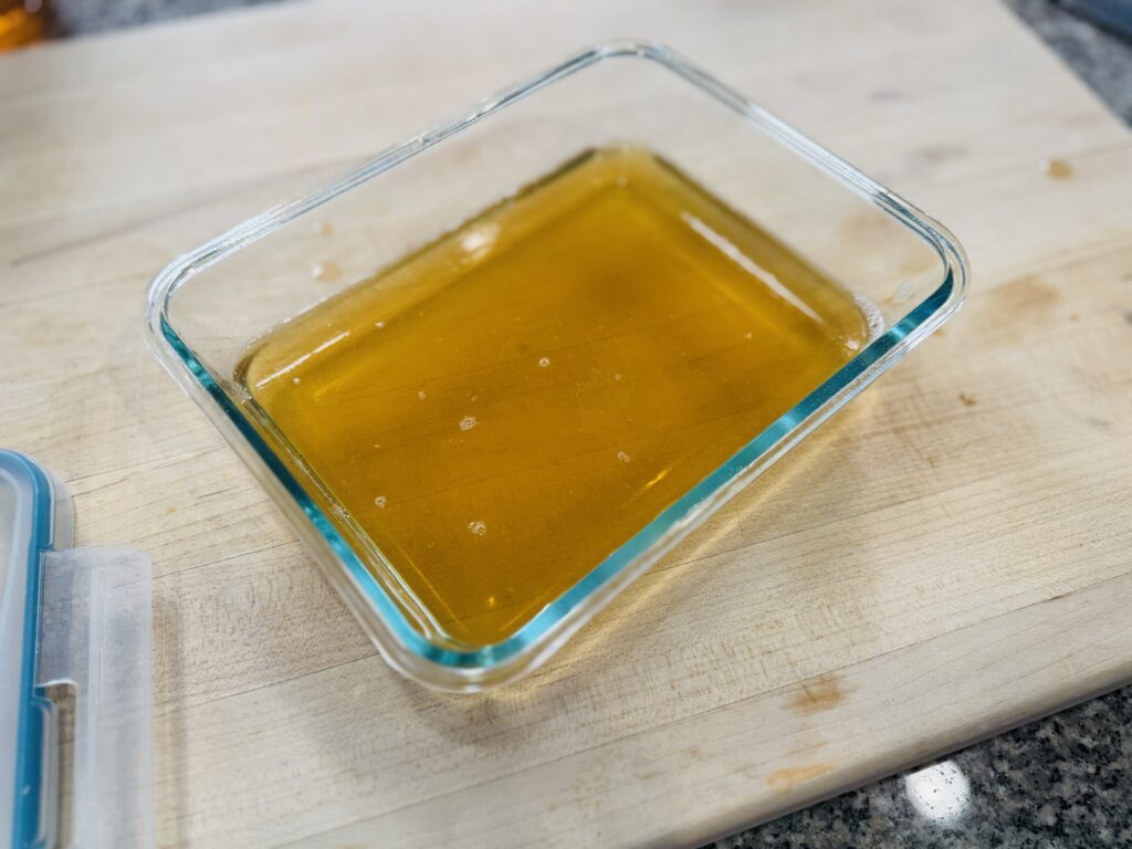 Apple juice gelatin mixture fully set in a glass container before slicing into gummies
