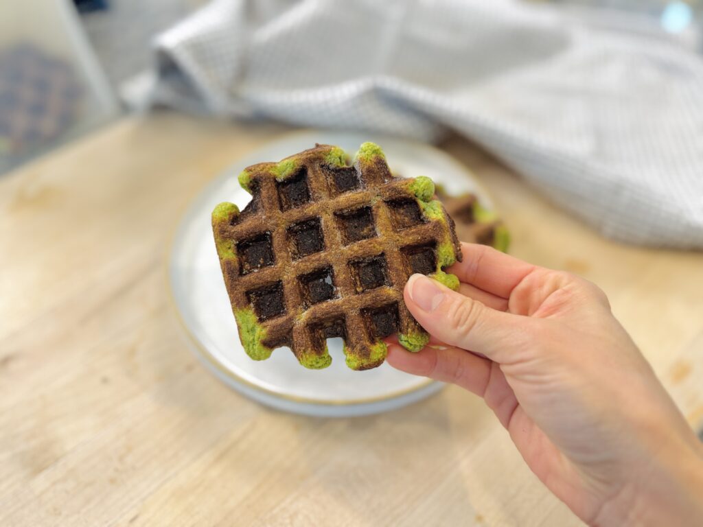Close-up of a spinach banana oat waffle showing its texture and green spinach flecks