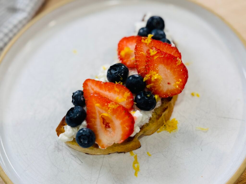 Cottage cheese toast topped with fresh strawberries, blueberries, and lemon zest