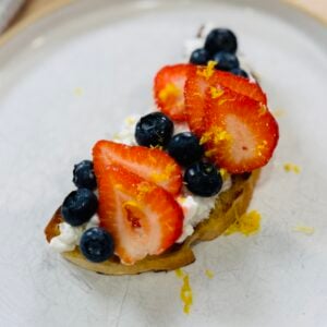 Cottage cheese toast topped with fresh strawberries, blueberries, and lemon zest