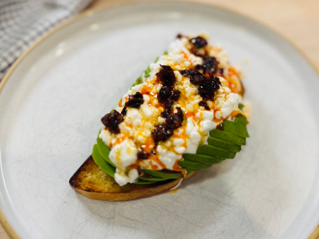 Cottage cheese toast with sliced avocado, chili oil, and honey on toasted sourdough