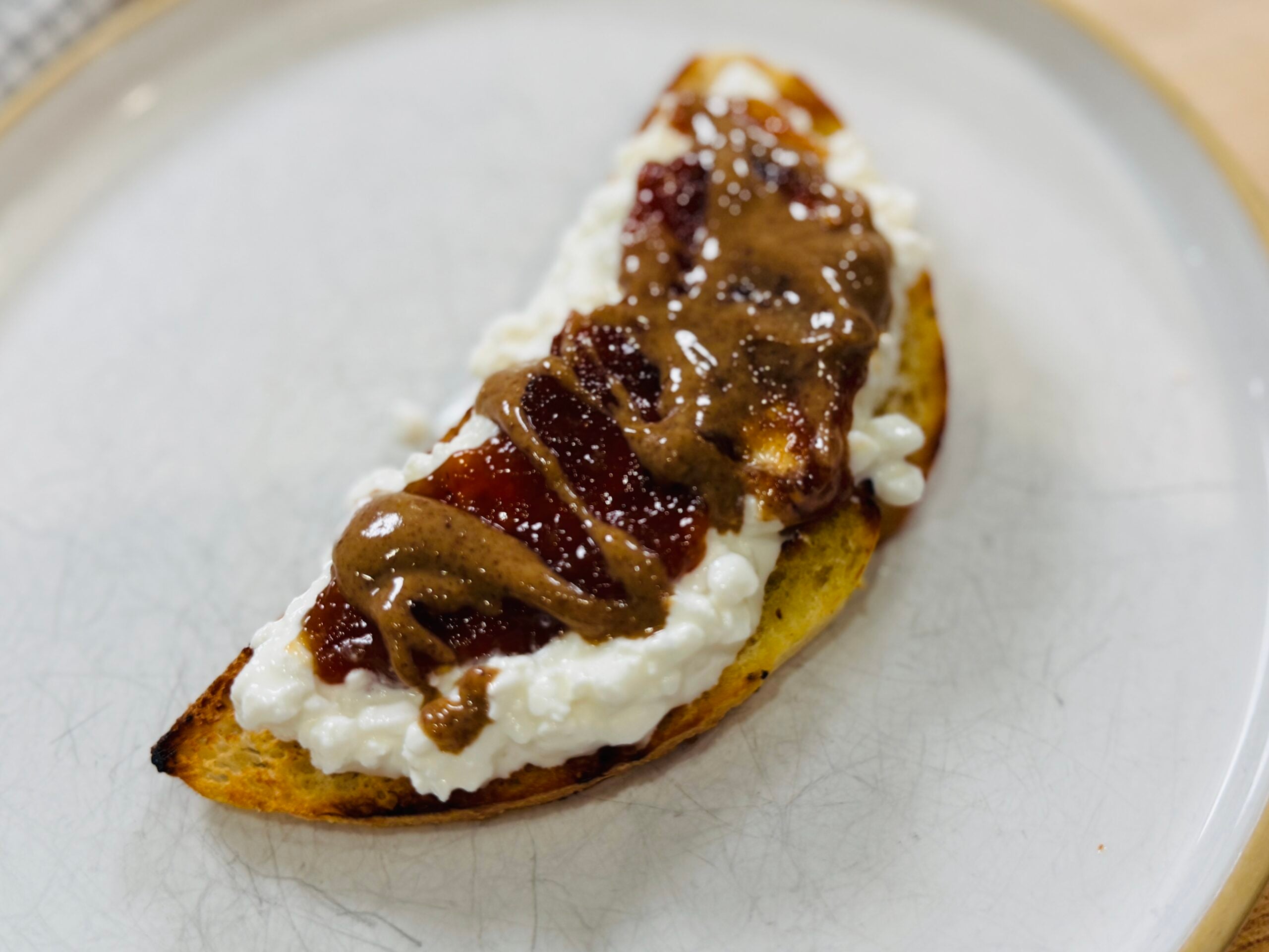 PB&J cottage cheese toast with strawberry jam and a peanut butter drizzle on sourdough