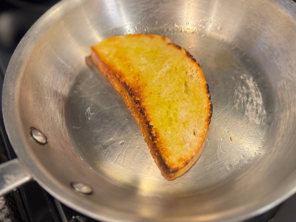 Sourdough bread toasting in a pan with olive oil until golden and crisp